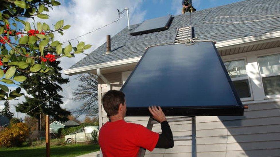 A man installs solar panels for a domestic hot water system in the US