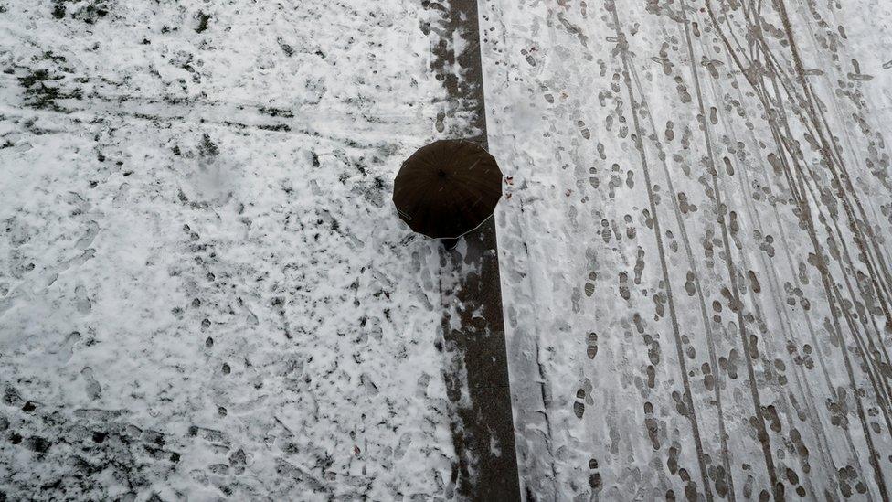 A person walks with an umbrella during heavy snowfall in Madrid's Rio park