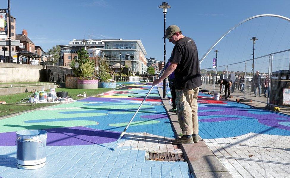 Alex Mulholland painting a mural on a disused bus lane on the Newcastle Quayside