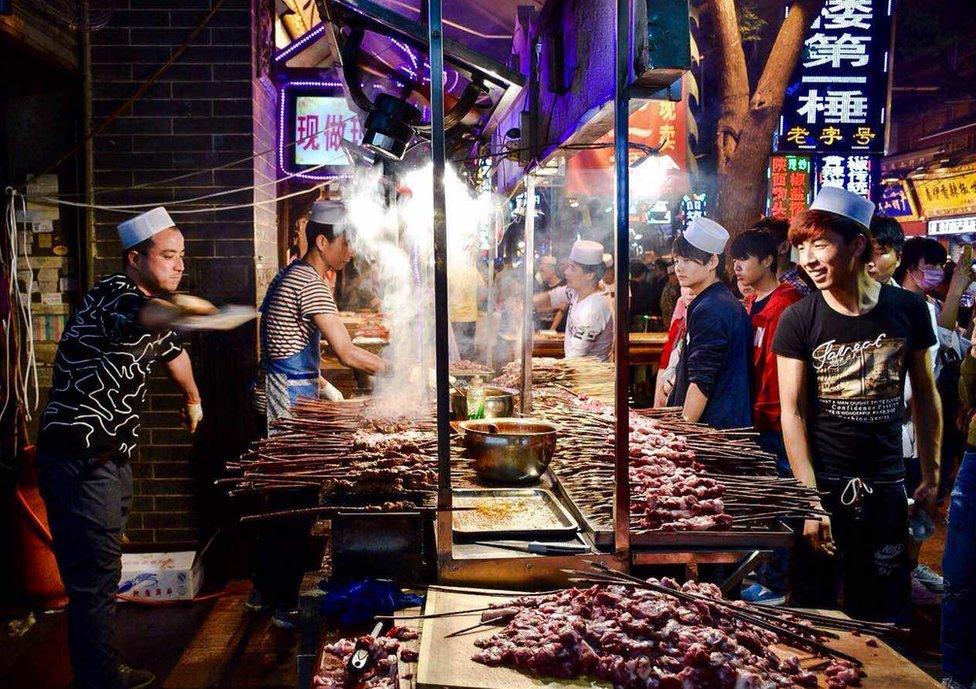 Street Vendors cook skewers of meat on a very busy street