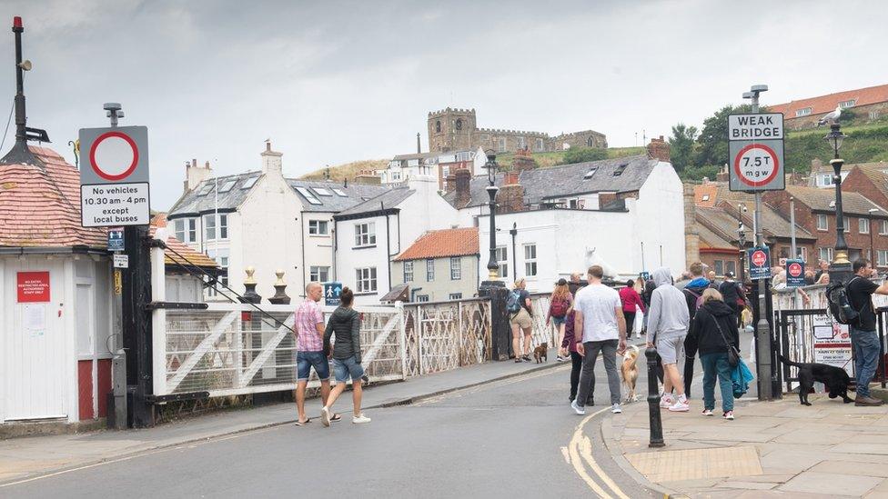 People walking across the historic swing bridge in Whitby