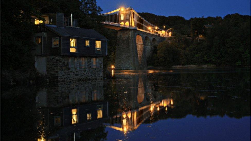 The Menai Bridge and Old Boat House are reflected in the water in this photograph by Bleddyn Jones-Pearson