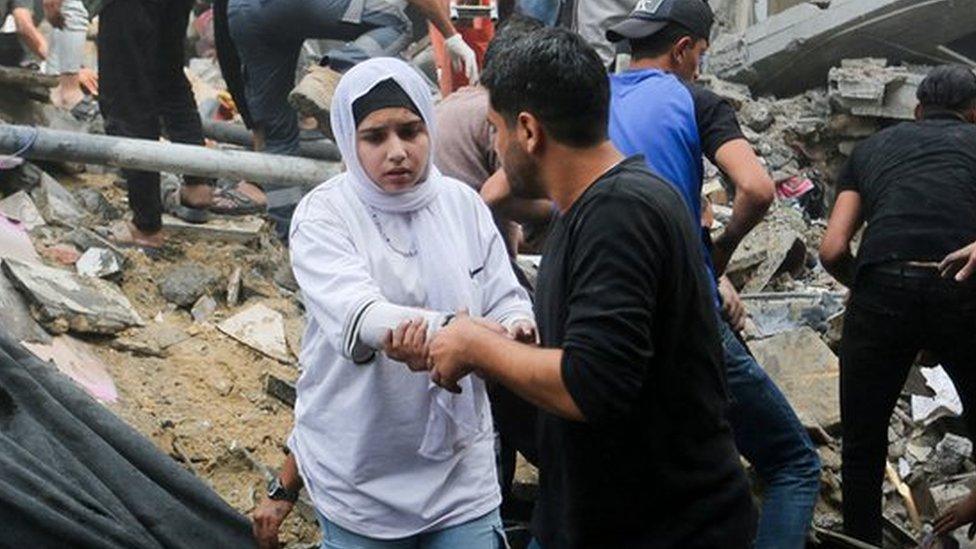 A girl is helped from rubble after an air strike.