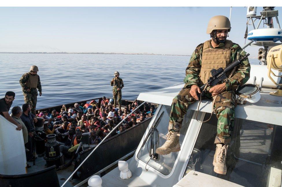 A Libyan coast guardsman watches over an operation to rescue illegal immigrants attempting to reach Europe