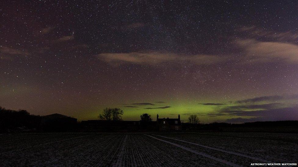 Green glow from Northern Lights behind a house