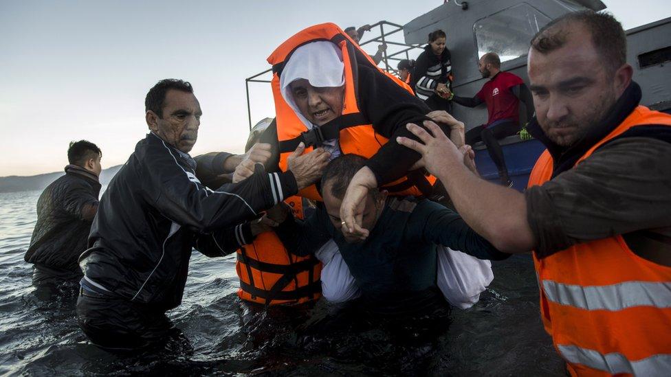 Volunteers help an elderly woman on the coast of Lesbos (1 Dec)