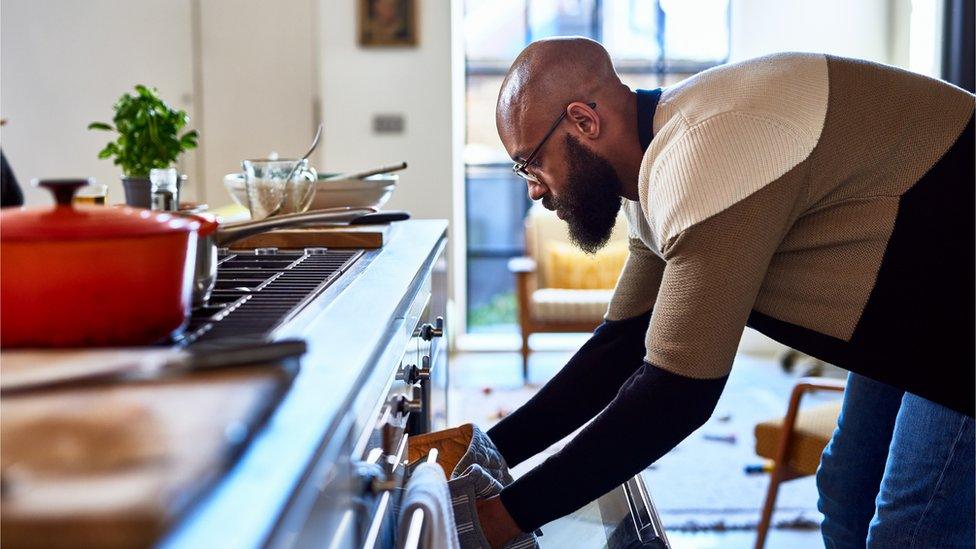 A man taking a baking tray out of the oven