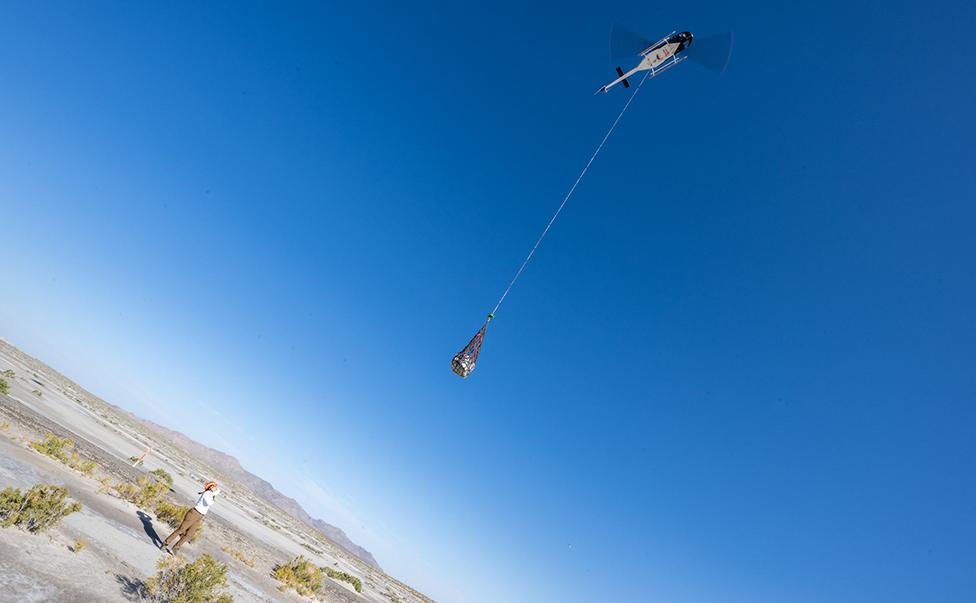 The capsule is lifted clear of the desert floor