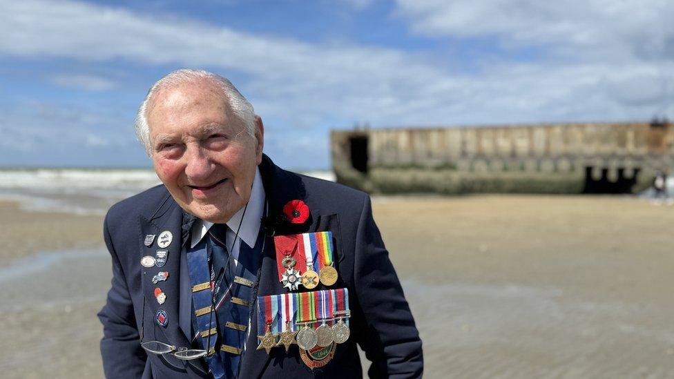 World War Two veteran Mervyn Kersh smiles on a beach wearing his military blazer and medals