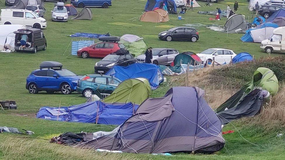 Damaged tents as campers survey the scene on Saturday morning