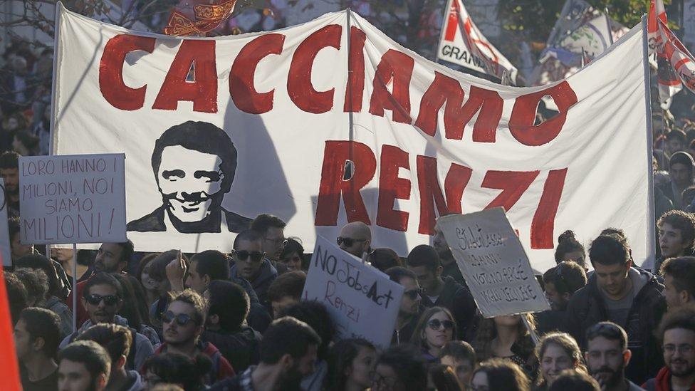 People march behind a banner portraying Italian premier Matteo Renzi and reading "Let's oust Renzi" during a demonstration ahead of a referendum over a constitutional reform.