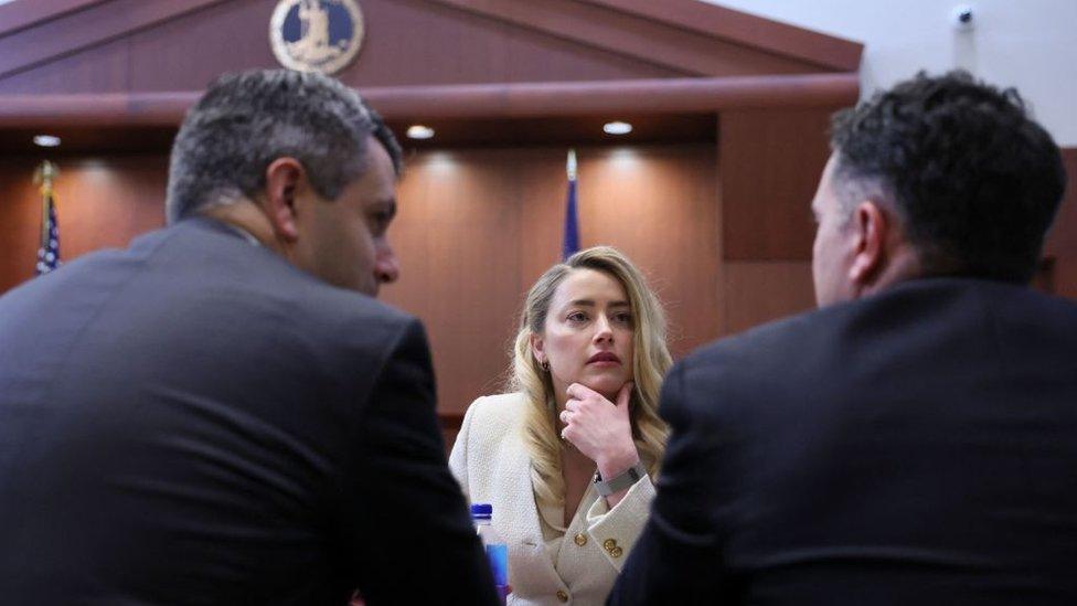 Actress Amber Heard talks to her attorneys during the defamation trial against her at the Fairfax County Circuit Courthouse in Fairfax, Virginia, April 20, 2022.