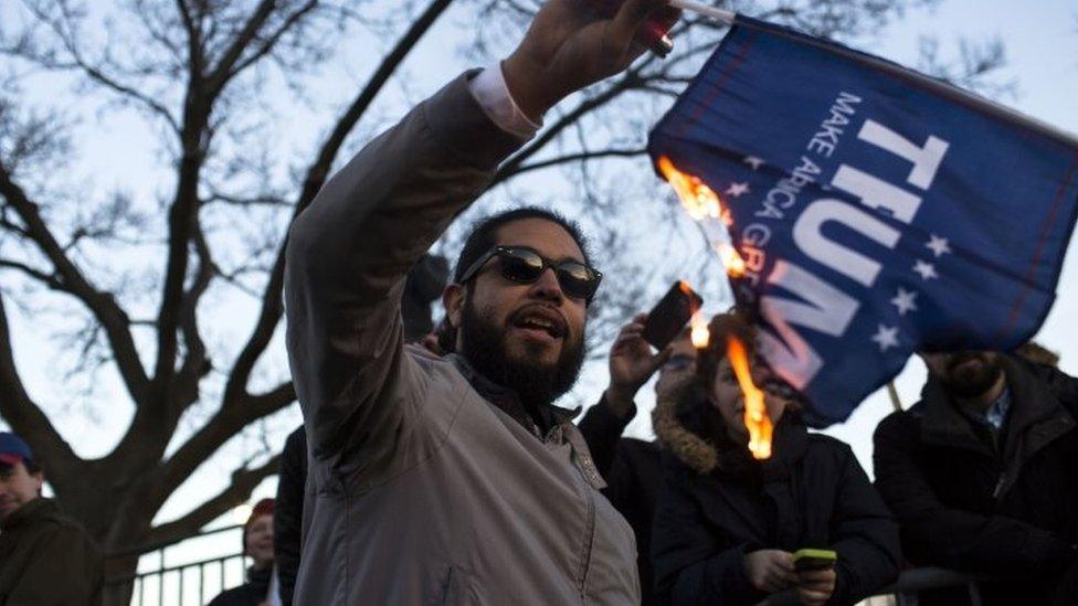 A protester burns a flag outside of the University of Illinois at Chicago Pavilion w