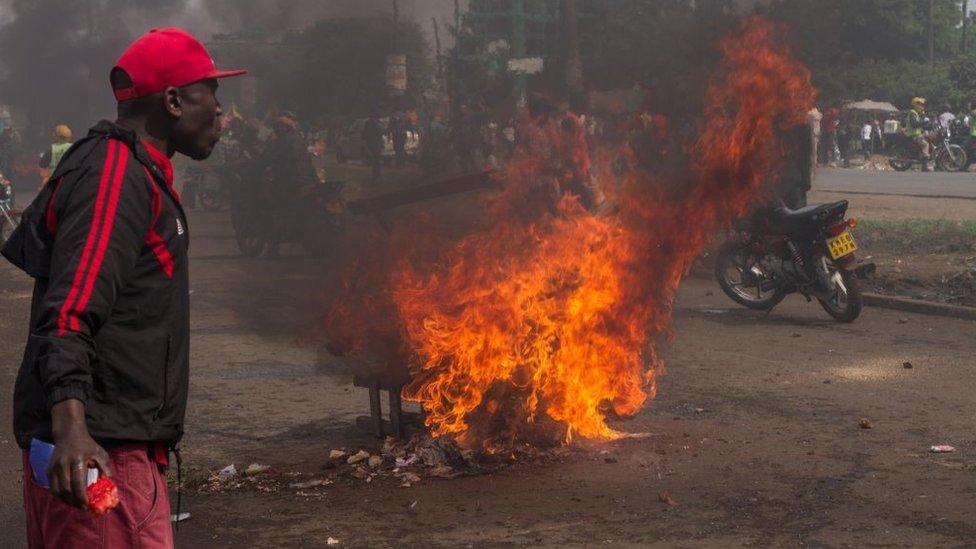 Burning road barricade seen during the protest as people walk near by. The welcome rally for returning opposition candidate Raila Odinga back to Kenya turned into a riot, with burning road barricades, stone throwing, tear gas grenades and water cannons (2017/11/17)