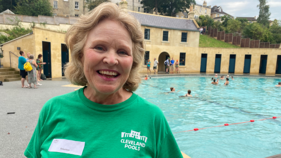 A picture of a woman in a green t-shirt by the pool