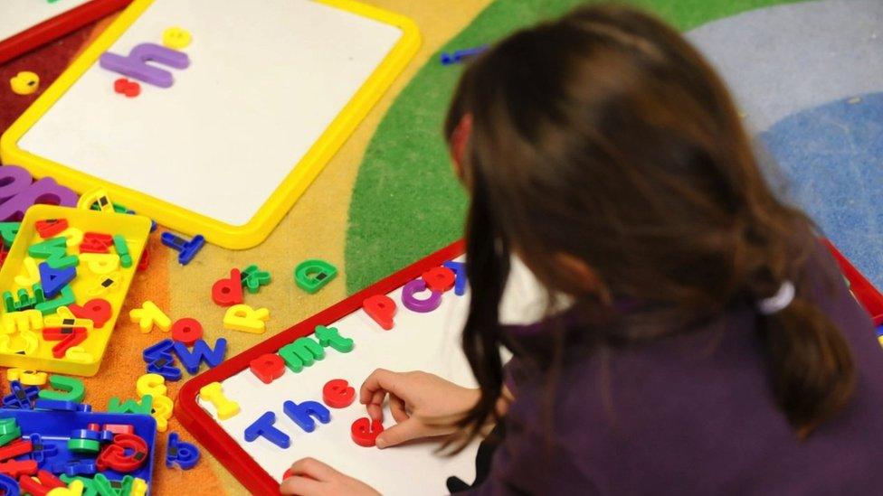 Child spelling with plastic letters