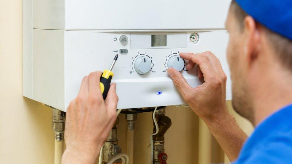 worker set up central gas heating boiler at home - stock photo