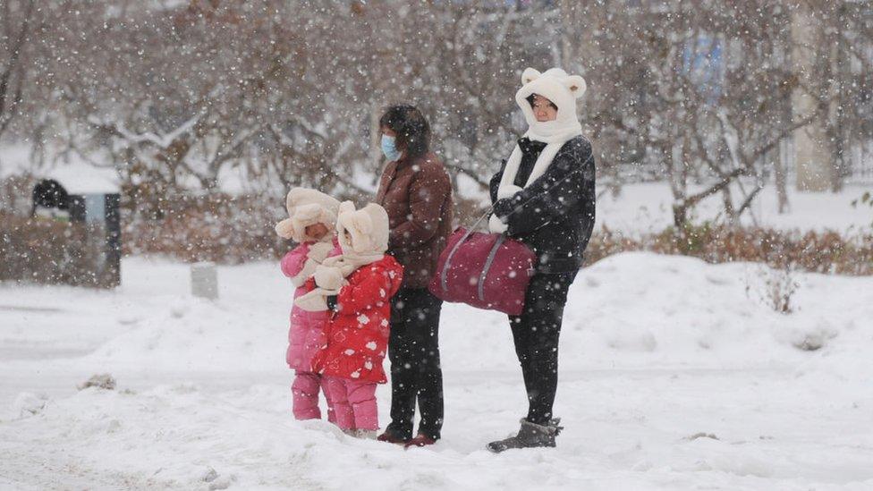 family walking through the snow wrapped up warm