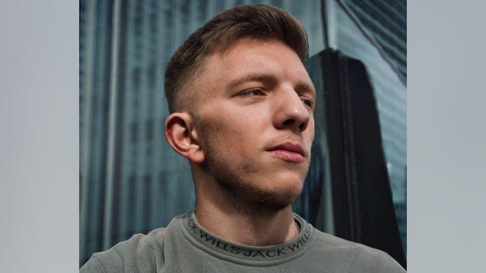 A man looking off to the right, wearing a grey jumper