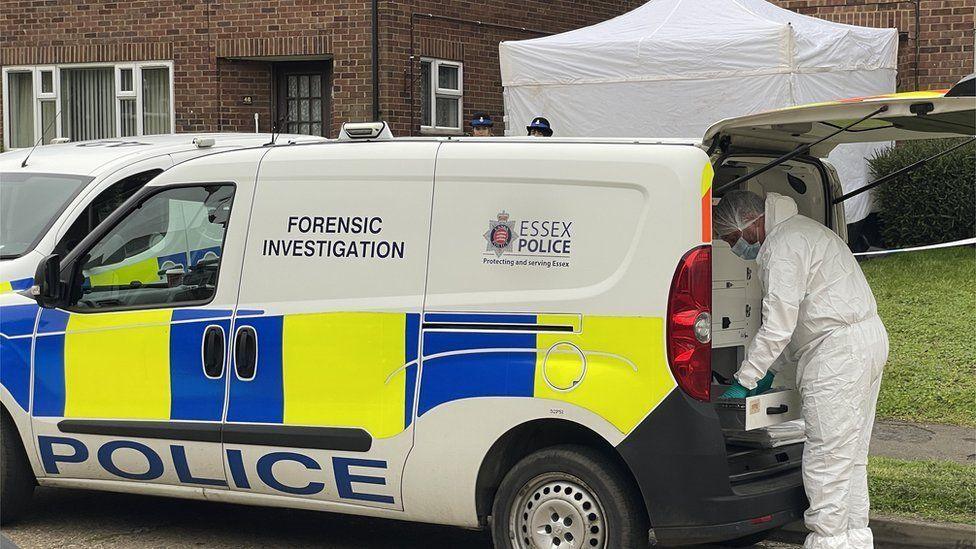 A police van parked at a property in Essex. There is a forensic officer and tent put up.