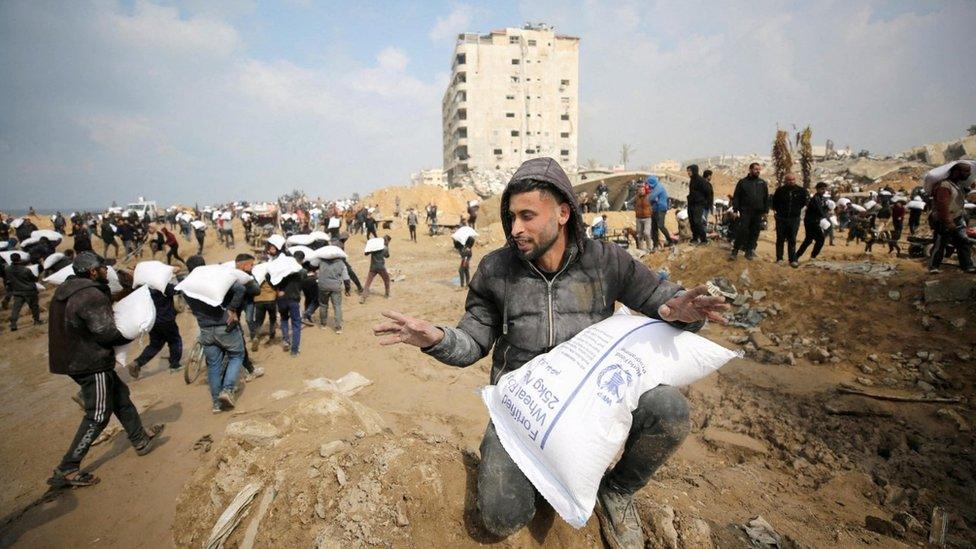 Men carry bags of flour taken from an aid truck near an Israeli checkpoint in Gaza City last month