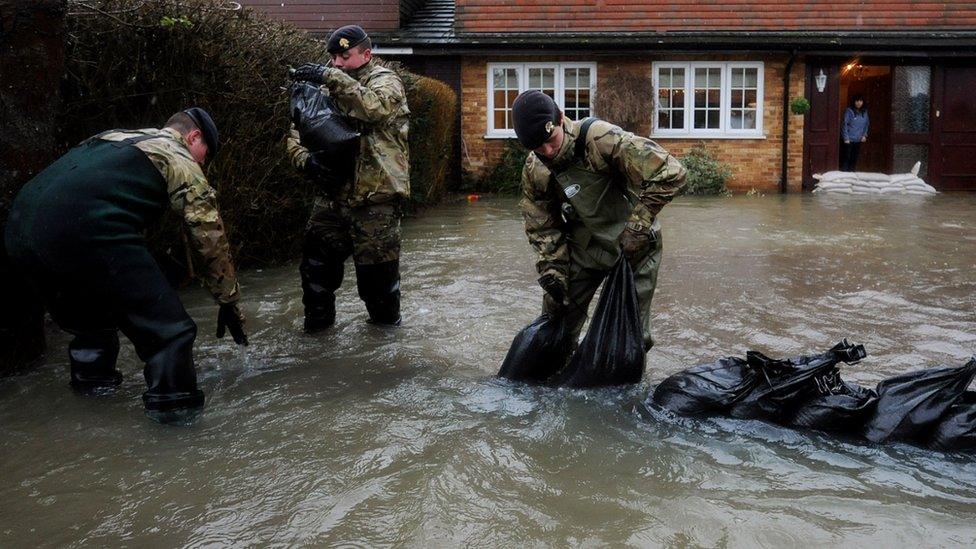 A woman looks from the door of her flooded home as soldiers place sandbags on her driveway in Wraysbury, near London. Photo: February 2014