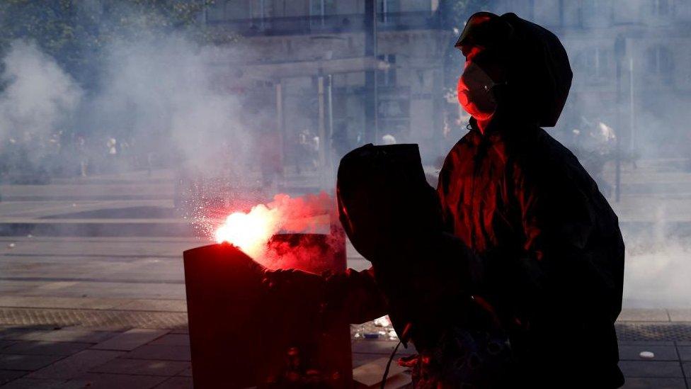 A masked protester holds a red flare during a protest on June 28, 2023 in Paris