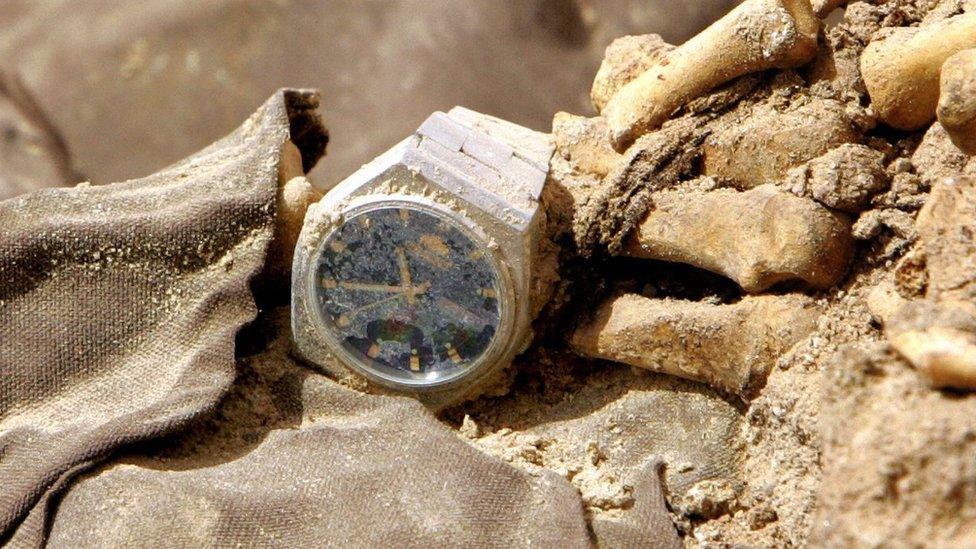 A wrist watch is seen on a human skeleton and clothes from persons allegedly executed during the regime of former President Saddam Hussein