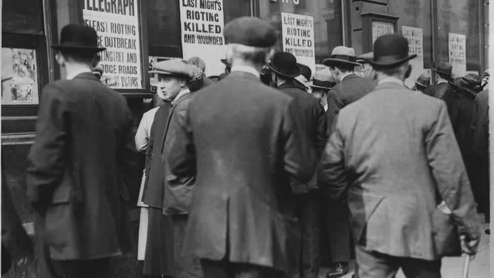 People gather outside the Belfast Telegraph offices to check through lists of those killed during rioting in 1920