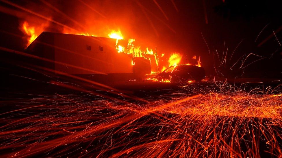 Embers blow in the wind as the Camp Fire burns a KFC restaurant