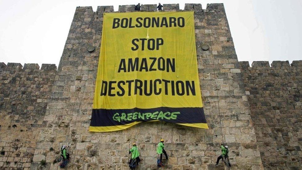 Greenpeace activists hang a large banner on the ramparts of the Old City of Jerusalem with a message to the visiting Brazilian president, on April 1, 2019