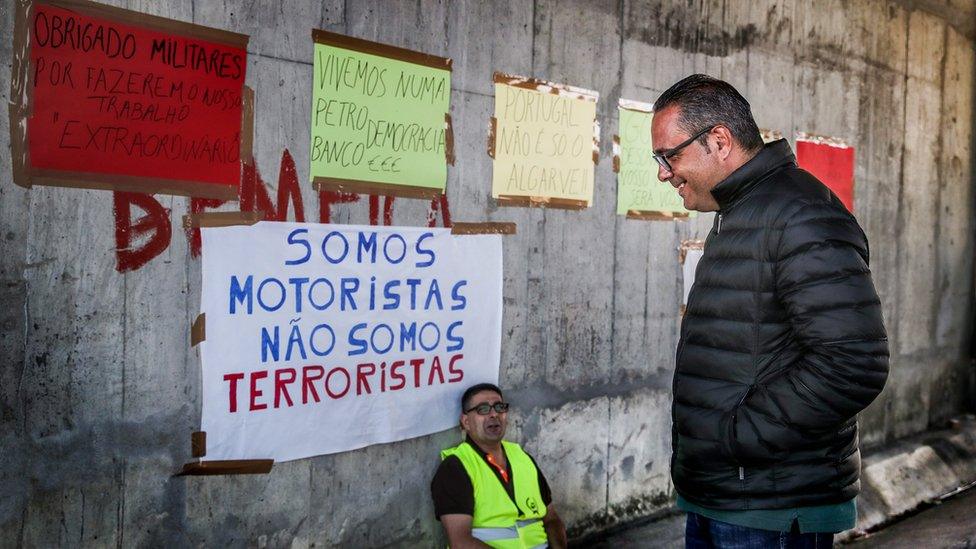 Spokesman for the national drivers union Pardal Henriques (R) speaks to a picketer outside the headquarters of the Logistics Fuel Company (CLC)