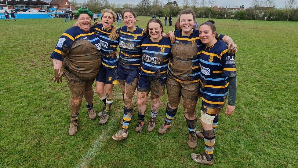 A women's rugby team covered in mud