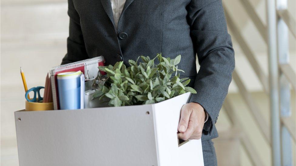 Woman walking out of office with box