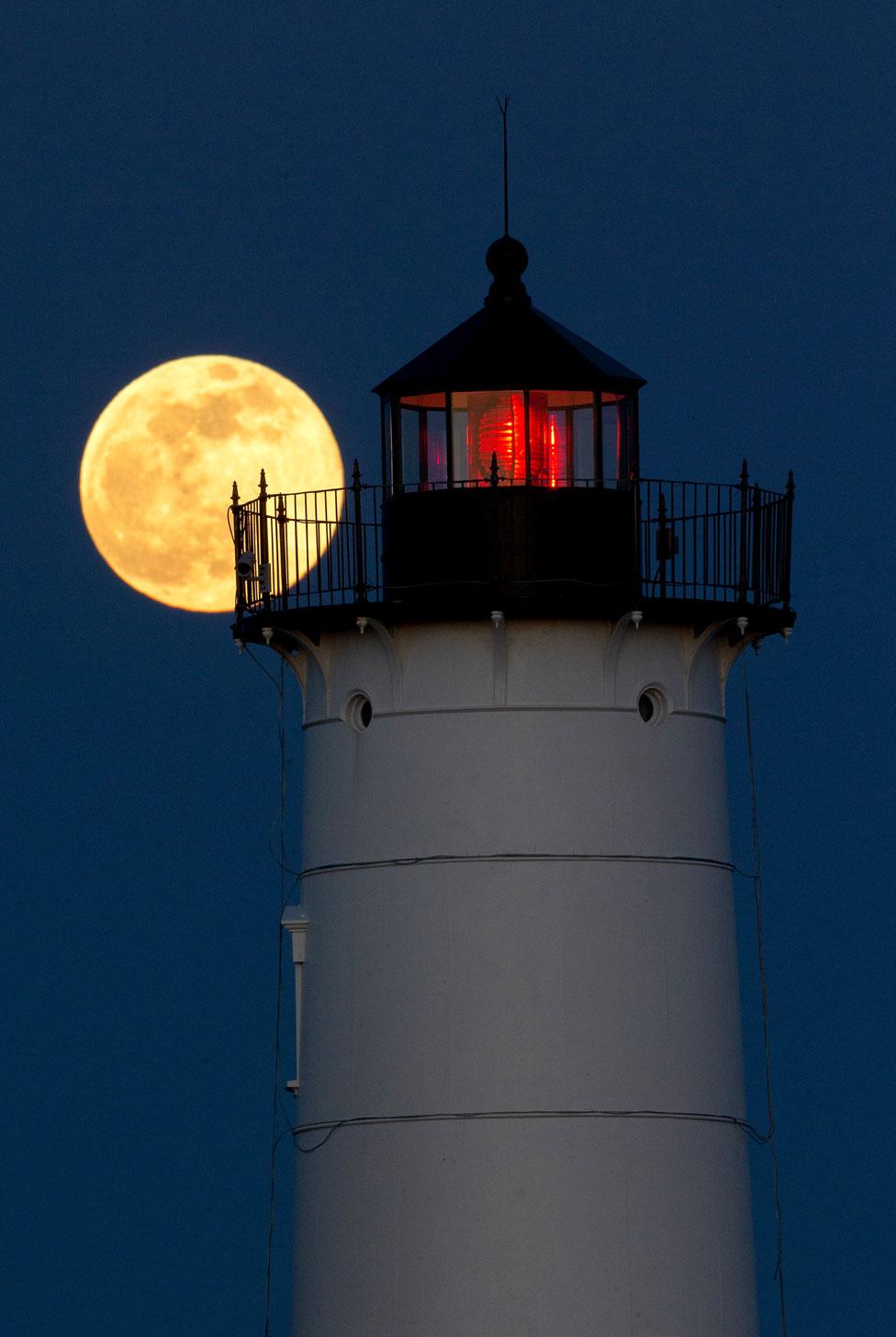 The supermoon rising behind the Nubble Lighthouse on Cape Neddick, in York, Maine, US