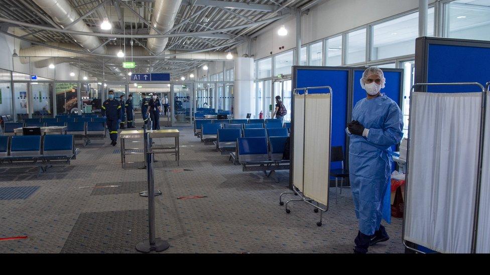 Medical staff wait to conduct tests on passengers arriving at Eleftherios Venizelos International Airport in Athens