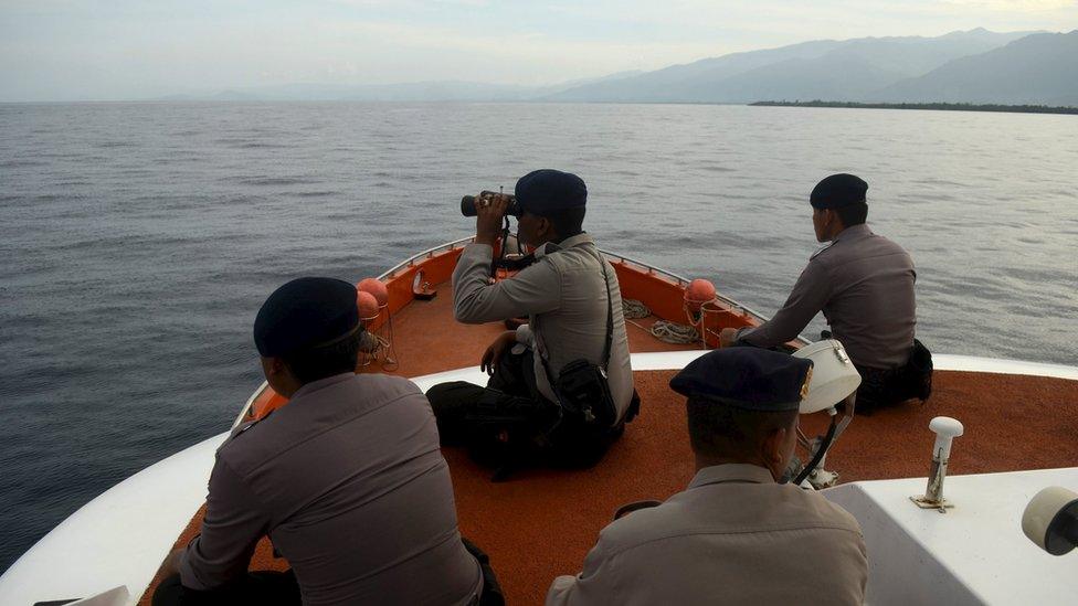 Rescue team members sit on top of a Basarnas boat as they take part in a search for passengers who were victims of a ferry sinking in the Gulf of Bone