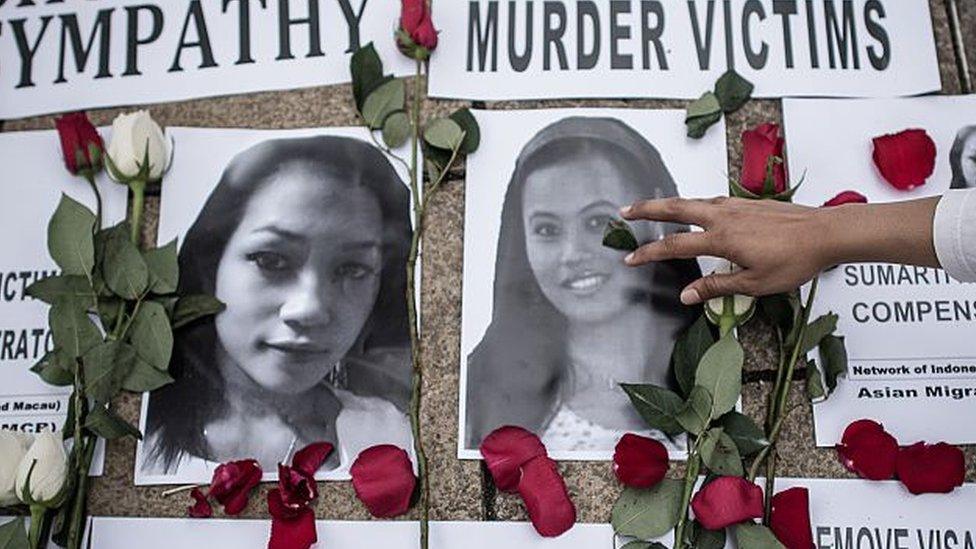 An Indonesian migrant worker lays rose petals over the pictures of murder victims in Hong Kong on 9 November 2014.