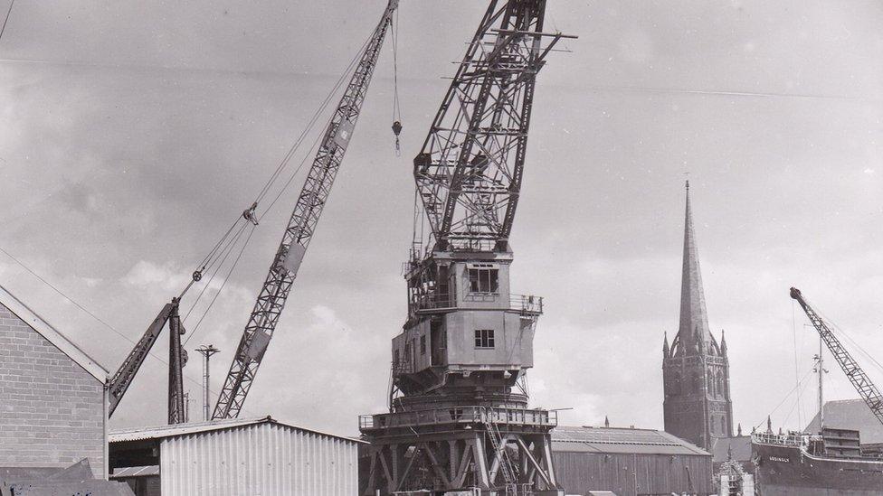 Image of crane at port with church spire in the background