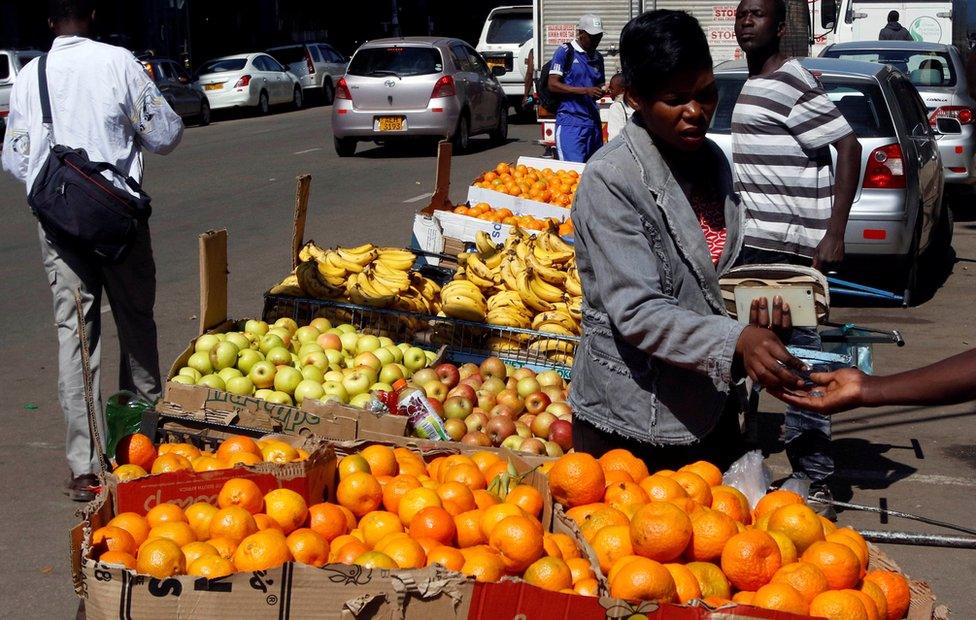 A woman buys oranges from a street vendor in central Harare, Zimbabwe