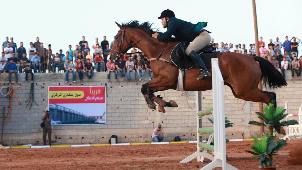 A rider jumps with his horse over a barrier during a local competition in Benghazi, Libya May 27, 2016.