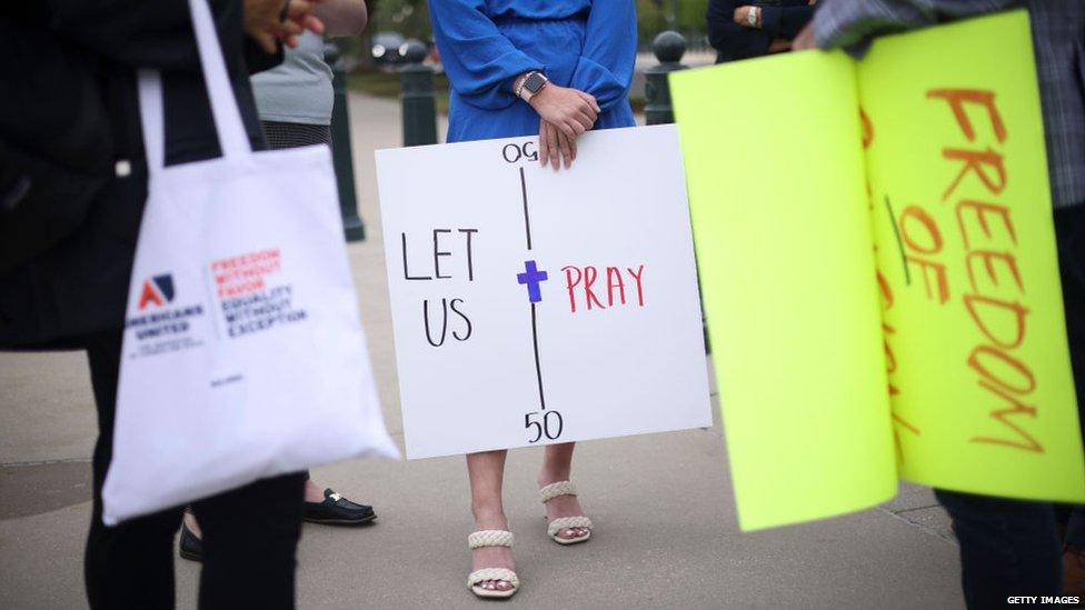 Supporters carry signs in favour of former high school coach who got in trouble for praying