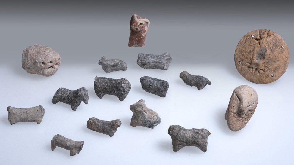 A collection of 15 small figurines made of stone, most shaped like people or animals