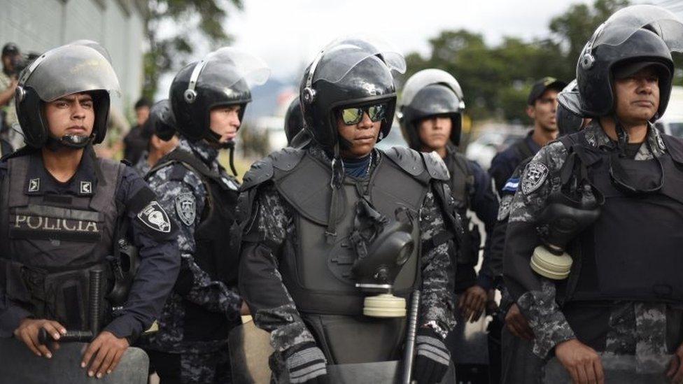 Police officers belonging to the COBRA Special Riot Command stand guard next to supporters of opposition candidate Salvador Nasralla as they hold a protest march on December 6, 2017 in Tegucigalpa.