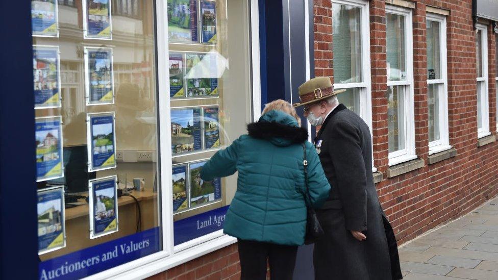 Couple looking at housing in estate agent in masks