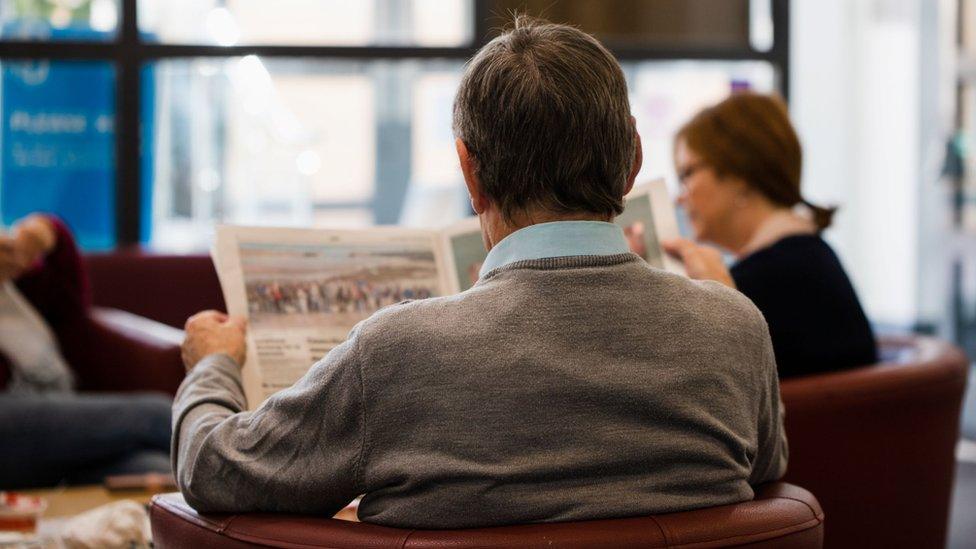 Man reading newspaper in the Hub