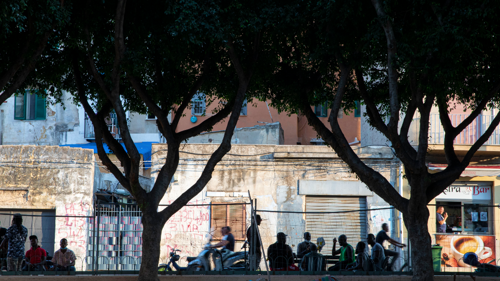 Migrants sitting at outside tables in alermo's Ballarò neighbourhood - Sicily