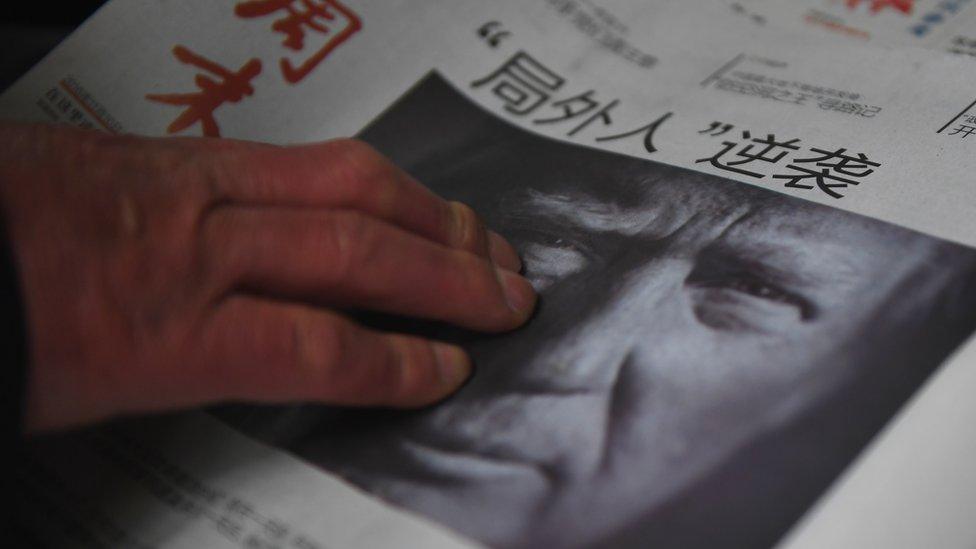 A man buys a Chinese newspaper, with the headline that reads 'Outsider strikes back