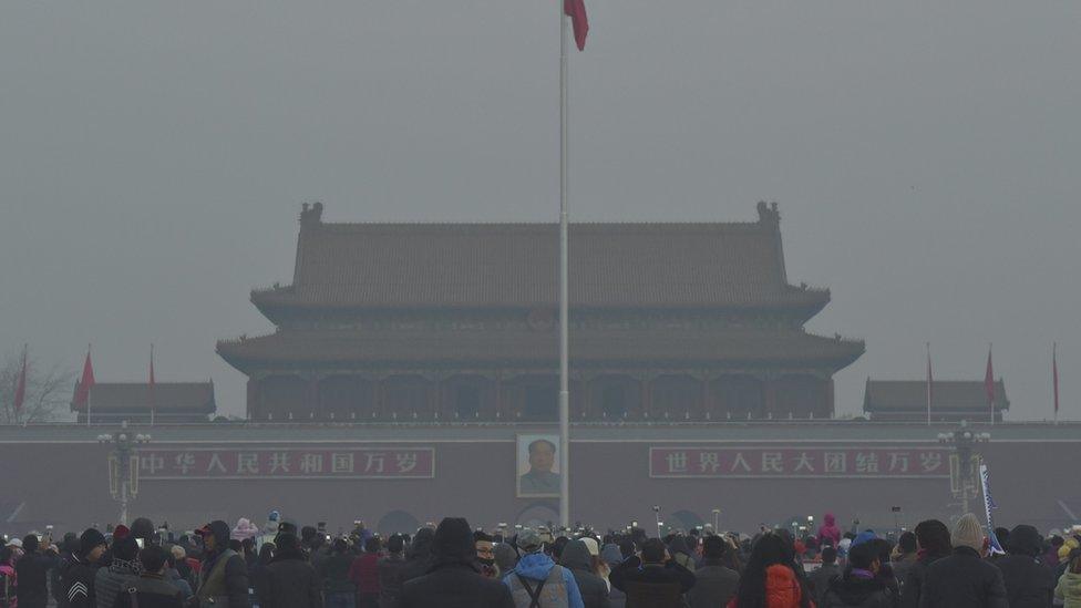 People watch a flag raising ceremony in front of the giant portrait of late Chinese chairman Mao Zedong, at the Tiananmen Square