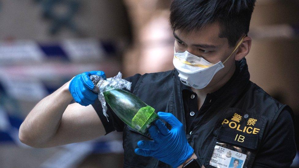 Hong Kong police officer inspects petrol bomb